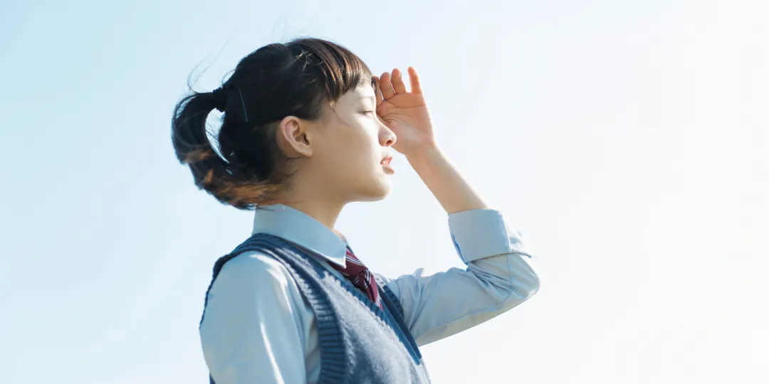 写真:女性の学生が遠くを見つめている